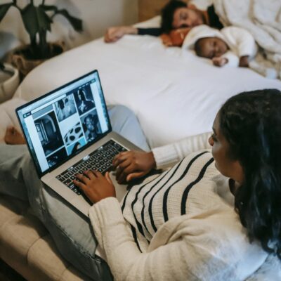 Woman freelancer working on netbook while husband and baby sleeping on bed